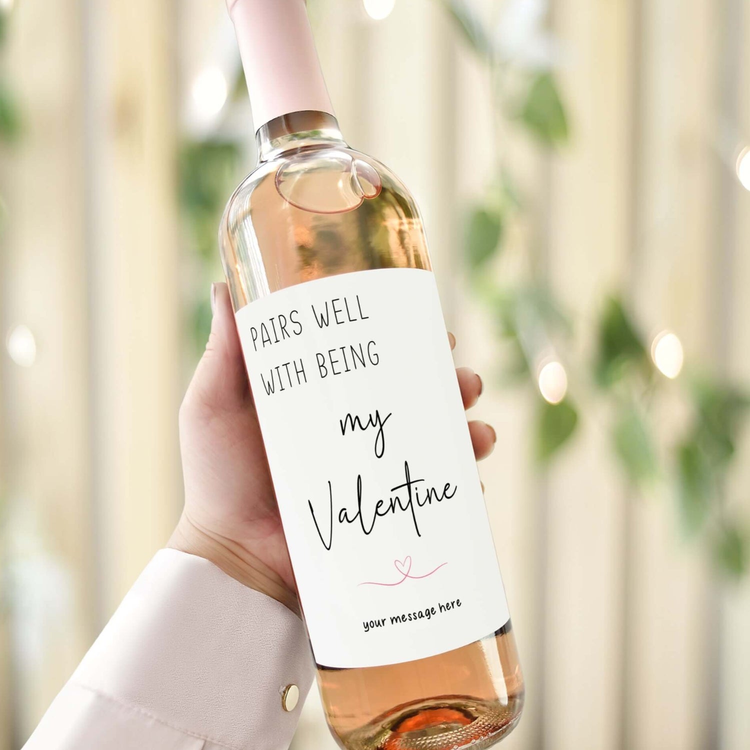 Personalised Valentine’s Day wine label reading 'Pairs well with being my Valentine,' held against a romantic backdrop.