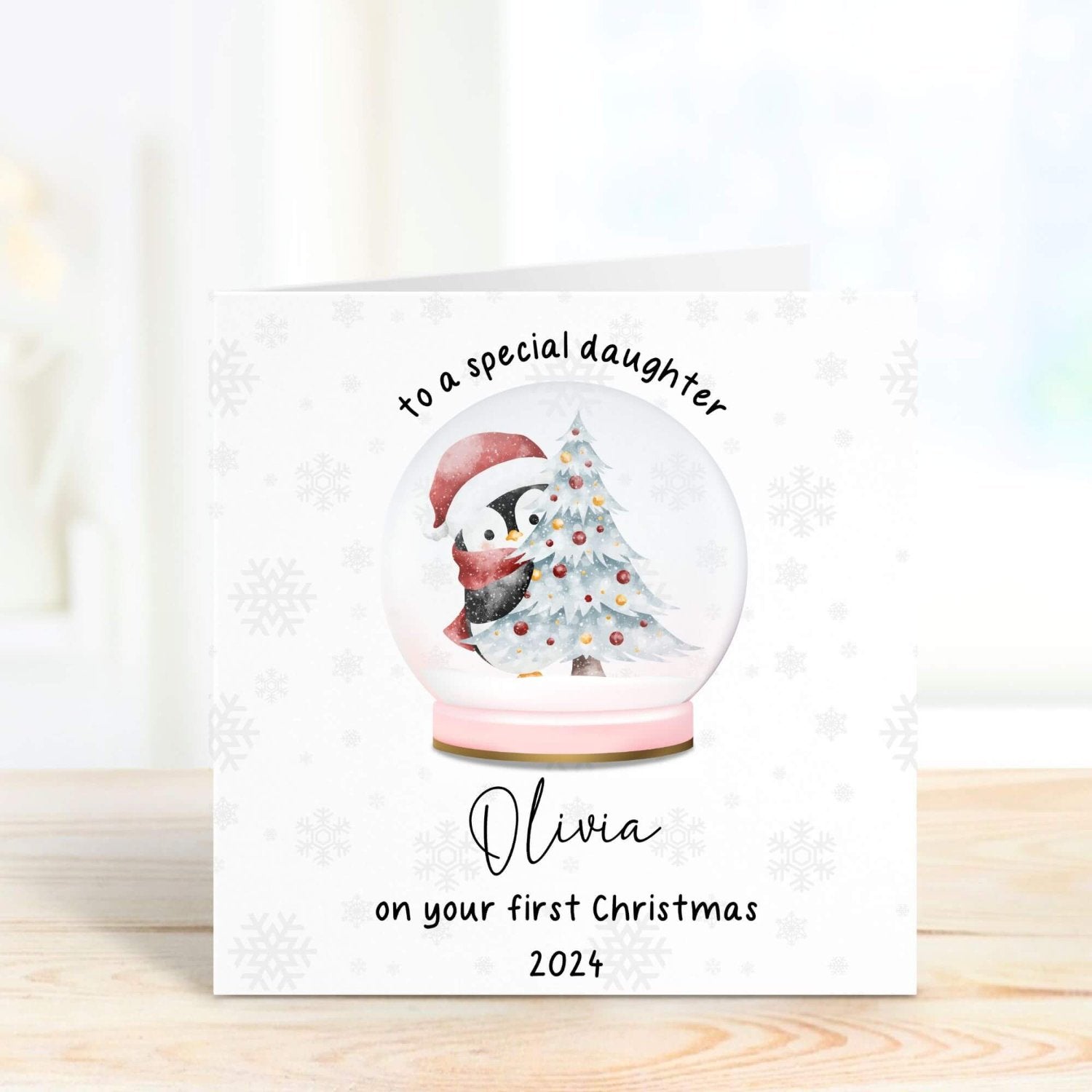 Adorable first Christmas card for daughter with a personalised message, featuring a festive snow globe design with a penguin and a decorated Christmas tree.