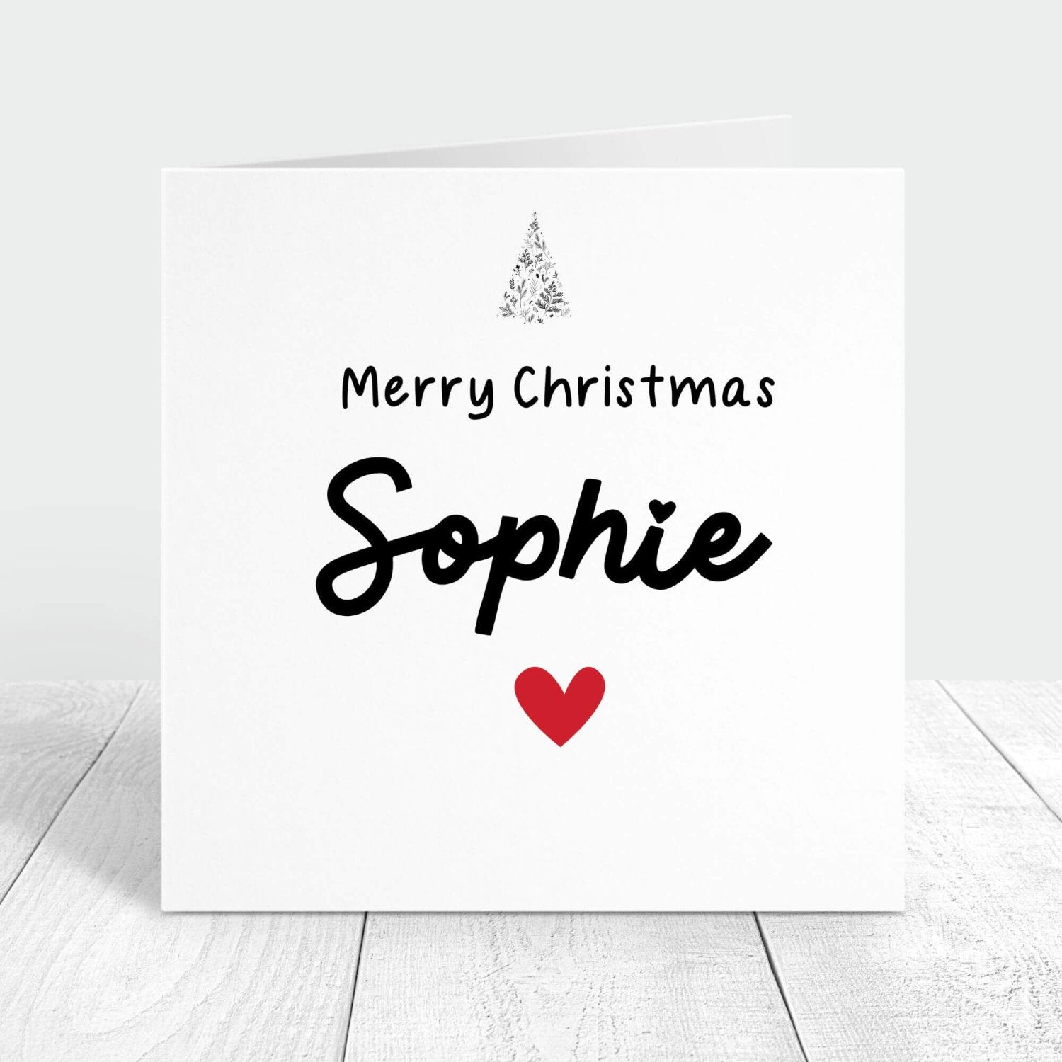 Personalised Christmas card with "Merry Christmas [Name]" message, featuring a festive tree and red heart. Perfect for sending holiday wishes with a custom name.