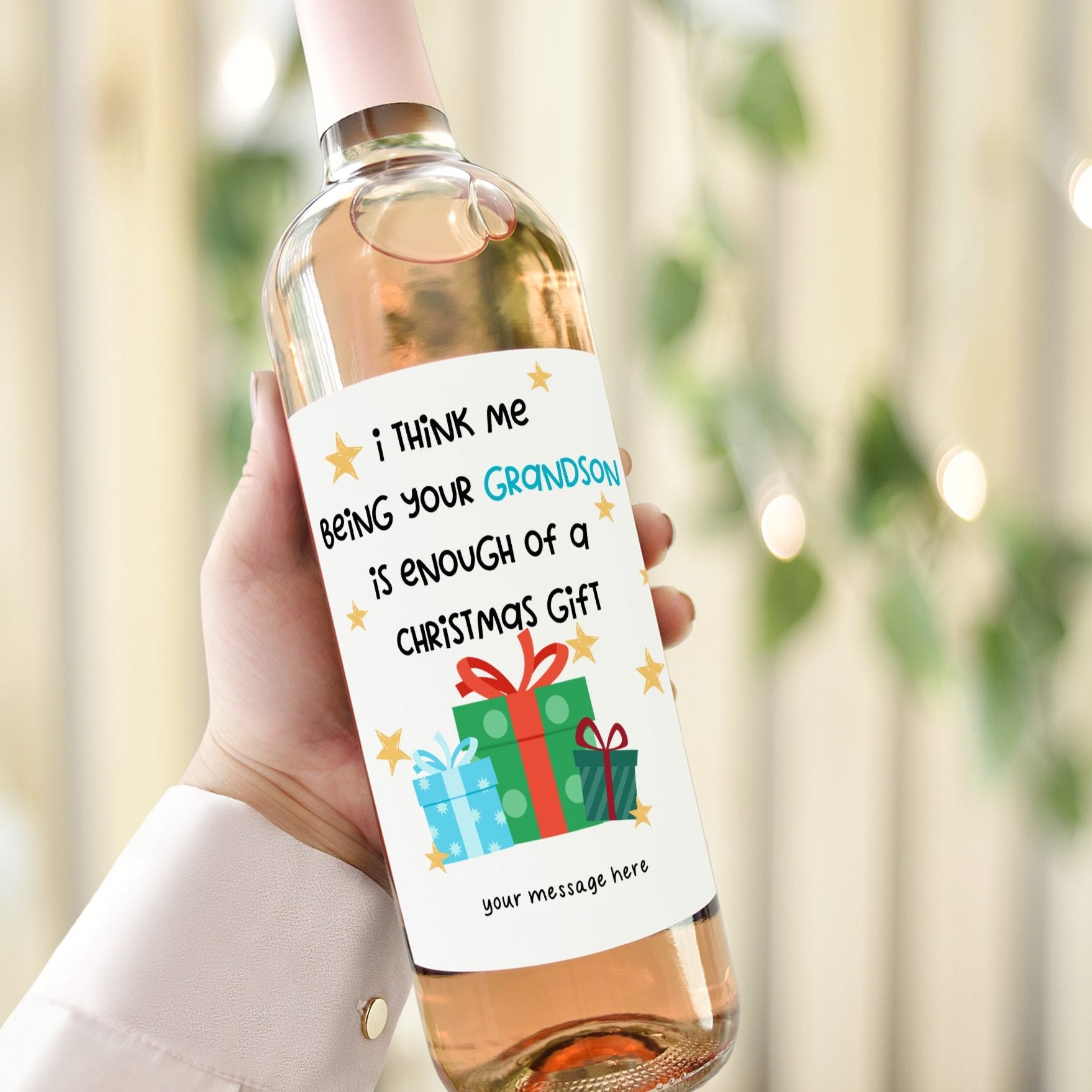 Hand holding a wine bottle with a humorous Christmas label for grandparents from their grandson, featuring stars and a festive gift graphic.