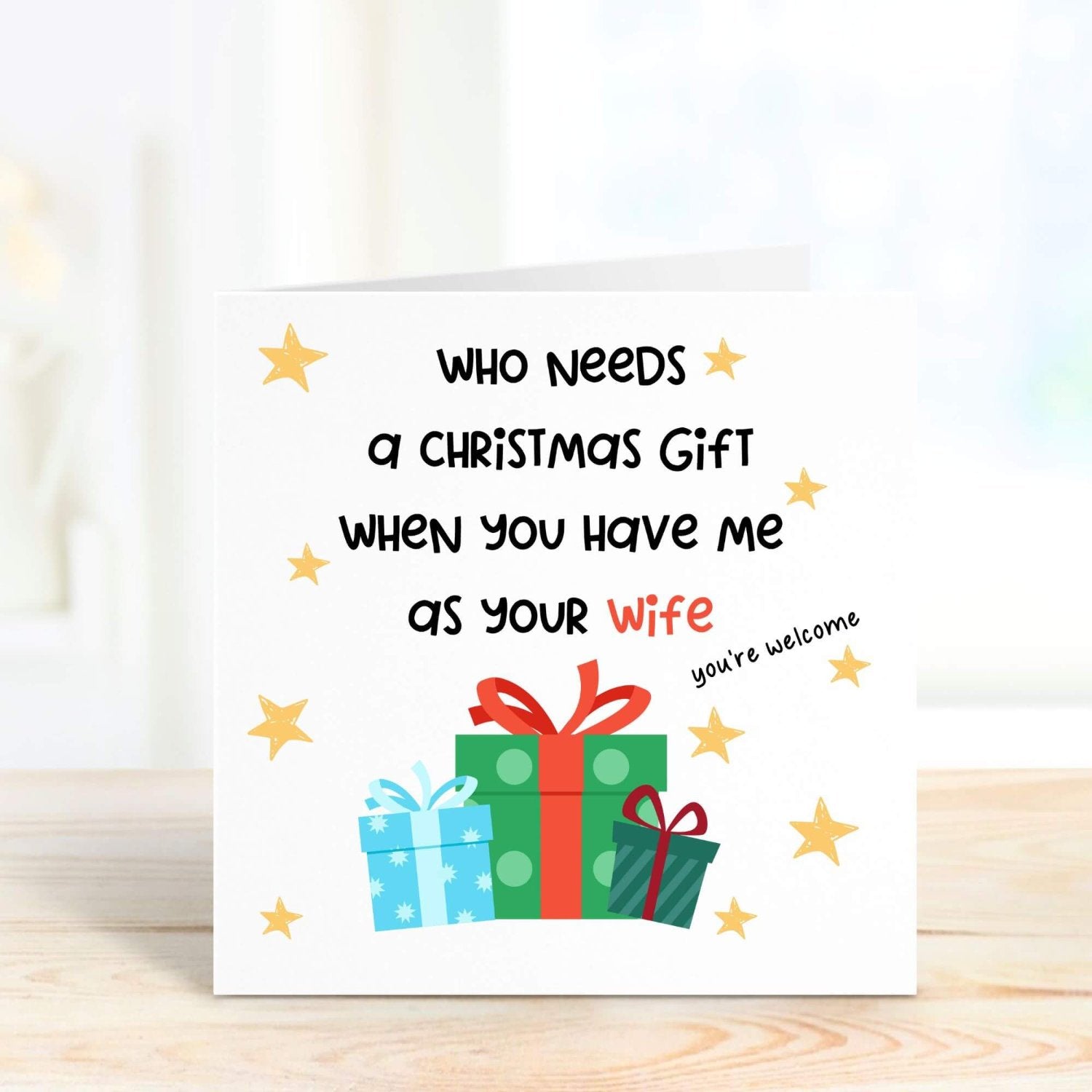 Humorous Christmas card for husband featuring gift boxes and stars, with the playful message, "Who needs a Christmas gift when you have me as your wife? You’re welcome."