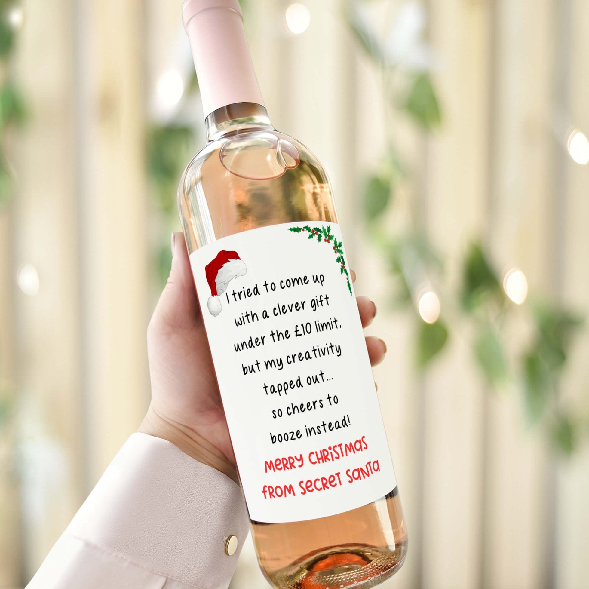 Wine bottle with a humorous Secret Santa label reading 'I tried to come up with a clever gift under the £10 limit, but my creativity tapped out... so cheers to booze instead! Merry Christmas from Secret Santa.'