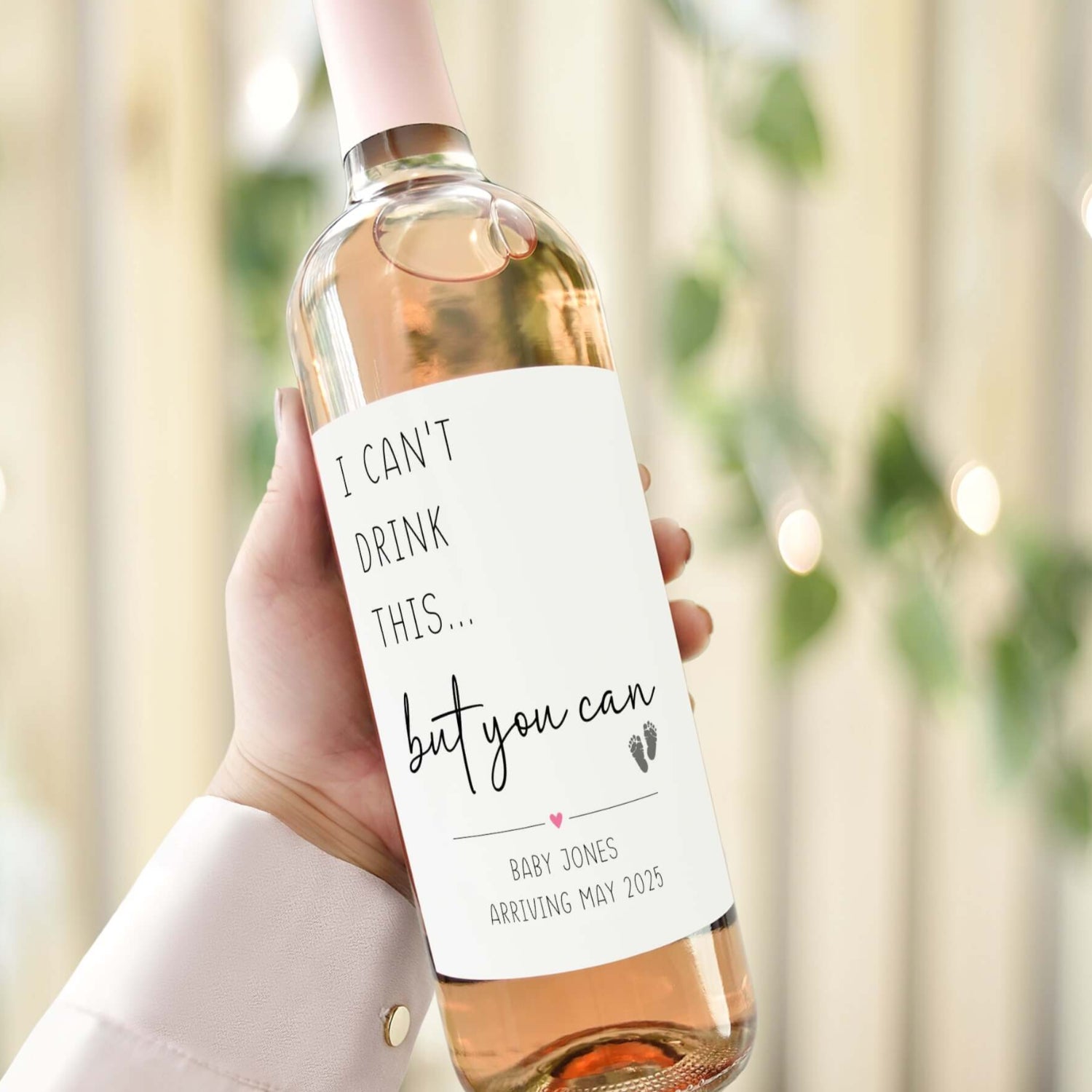 A wine bottle with a custom pregnancy announcement label reading "I can’t drink this… but you can," personalised with baby arrival details.